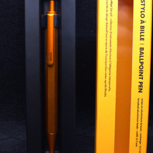 Orange pen in a black and yellow box on a dark background