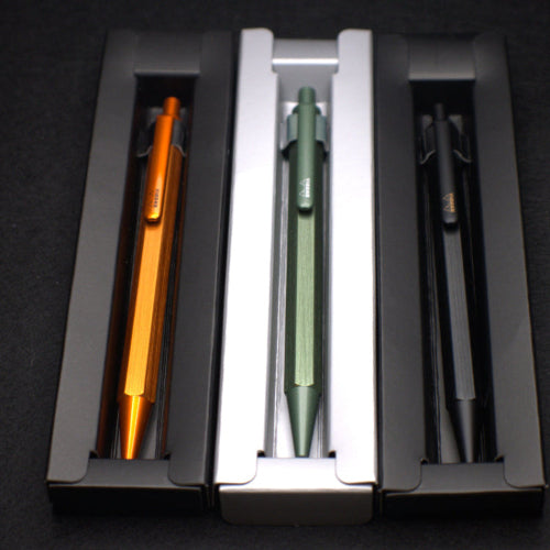 Three pens in a holder with orange, green, and black colors on a dark background.