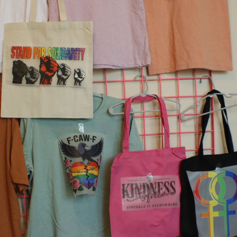Collection of t-shirts and bags with various designs on a grid wall.
